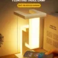A modern table lamp with a geometric design emits a warm glow. It features a 10W wireless charging pad, shown charging a smartphone. Text reads "Floating Table Lamp.