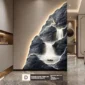 Modern interior with a wall featuring a backlit mural of a waterfall, stag, and boat on a rocky background; marble floor and muted tones.